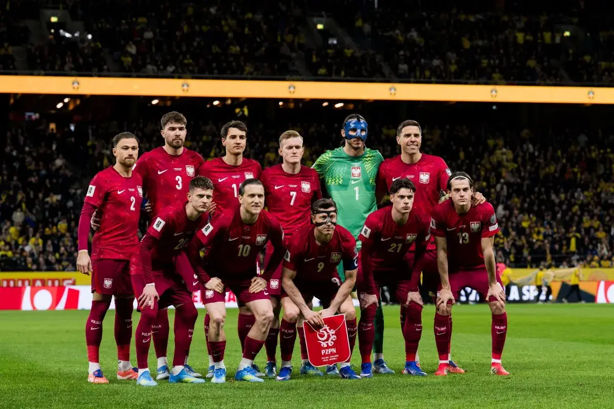 Drużyna Polski w piłce nożnej gotowa do gry. Piłkarze w bordowych strojach, bramkarz w zielonym.